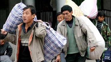 Unemployed Chinese migrant workers shouldering their belongings arrive at the Xuchang Railway Station in Xuchang 