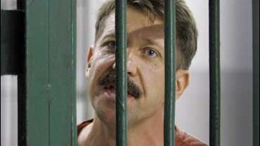 Alleged Russian arms dealer Viktor Bout talks to reporters across the bars at criminal court in Bangkok 