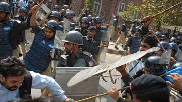 Pakistani police officers use their baton to disperse lawyers during clashes in Lahore, Pakistan 