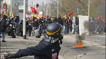 A riot police officer throws a stun grenade towards a group of anti-NATO activists, during clashes near the German border at the Europe bridge, east of Strasbourg, France 