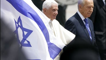 Pope Benedict XVI, left walks with Israel President Shimon Peres as they walk past an Israel flag during the welcoming ceremony for the pope at Ben Gurion International airport, in Tel Aviv 
