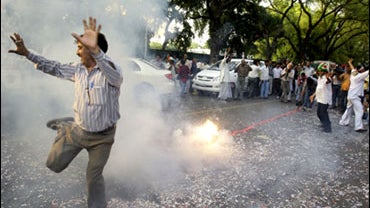 A Congress party supporter dances in celebration as fireworks go off outside the party headquarters in New Delhi, India, Saturday, May 16, 2009. 