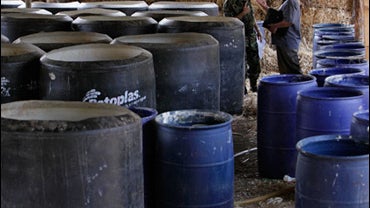 Navy officials stand among containers at a clandestine drug laboratory after an operation near Culiacan, Mexico, Tuesday, June 16, 2009. 