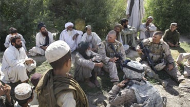 U.S. Marines from the 2nd Marine Expeditionary Brigade, 1st Battalion 5th Marines sit with Afghani residents of the village of Noghara in the Nawa district in Afghanistan's Helmand province Friday July 3, 2009. 