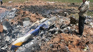 an unidentified man observes the scene of a plane crash near the village of Jannatabad, outside the city of Qazvin 