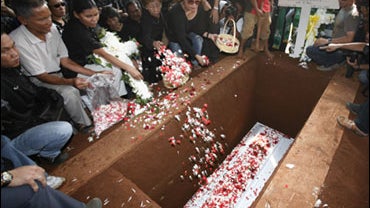 Relatives and colleagues sprinkle flowers on the coffin of Evert Mocodompis, an employee of J.W. Marriott hotel who was killed in Friday's bomb blast, during his burial at a cemetery in Jakarta, Indonesia, Monday, July 20, 2009. The terrorist attacks that 