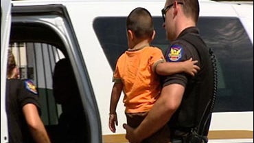 Phoenix police carry the 2-year-old boy who, after a traffic pullover, was found with a bag of Methamphetamine stuffed in his diaper. The toddler was placed in the care of Child Protective Services. The father was arrested. 