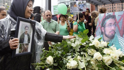 A woman places a white rose in front of a picture showing Iranian Sohrab Aarabi, 19, who disappeared during a June 15 protest in Iran, in Berlin, Saturday, July 25, 2009. 