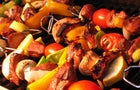 Kebabs cooking on the grill with metal skewers. 