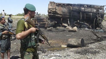 Afghan security forces stand guard near a burnt fuel tanker in Kunduz, north of Kabul, Afghanistan, Friday, Sept. 4, 2009. 