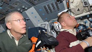 Mission specialists Patrick Forrester (left) and Tim Kopra work on the flight deck of space shuttle Discovery. 