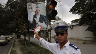 An Afghan traffic police officer manages a crossing under Afghanistan president Hamid Karzai's election poster, in Kabul, Afghanistan, Wednesday, Sept. 16, 2009. 