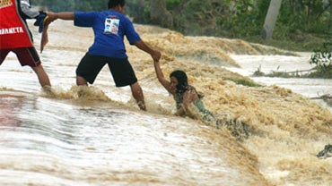 A woman holds on to a man as strong currents pull her away from the streets in Rosales town, northern Philippines, on Friday, Oct. 9, 2009. 