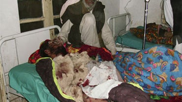 A local resident sits alongside a victim of suicide bombing, at a local hospital in Lakki Marwat, Pakistan, Friday, Jan. 1, 2010. 