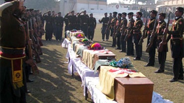 Pakistani paramilitary soldiers salute before caskets of their comrades killed in Friday's suicide car bombing during a funeral prayer at their base camp in Bannu, Pakistan, Saturday, Jan. 2, 2010. 