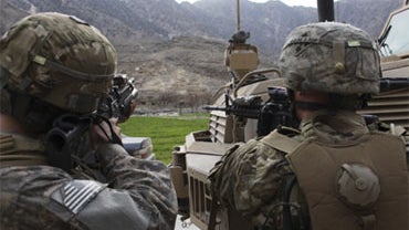 U.S. Army soldiers of the 2-12 Infantry stand behind an armored vehicle looking for hiding Taliban militants at the start of a patrol in Sundray, a village in the Pech Valley, Kunar province, northeastern Afghanistan, Friday Jan. 22, 2010. 