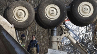 Emergency ministry workers look on as part of the landing gear is seen in the wreckage of the Polish presidential plane which crashed early Saturday in Smolensk, western Russia, Monday, April 12, 2010. 