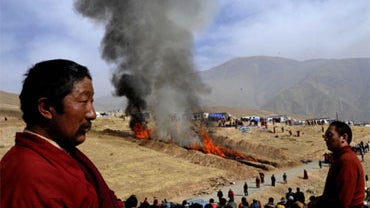 Tibetan monks sit on a hillside to offer prayers during a mass cremation for victims of Wednesday's earthquake in Yushu County, west China's Qinghai province, Saturday, April 17, 2010. At least 1144 people died in the Yushu earthquake, with 11774 injured. 