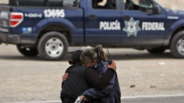 Two municipal police officers embrace after they were ambushed by unknown gunmen in the northern border city of Ciudad Juarez, Mexico, Friday April 23, 2010. 