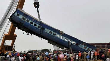 A railway crane lifts a mangled compartment of the derailed train, in Sardiha near West Midnapore district of West Bengal state, about 95 miles west of Calcutta, India, Saturday, May 29, 2010. 