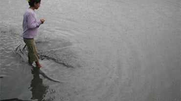 A girl stands amid rain water in a street in Amatitlan, south of Guatemala City, Saturday, May 29, 2010.  