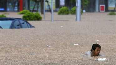 In this photo taken Wednesday, June 9, 2010, a Chinese resident tries to move through floodwaters triggered by rainstorms in Wuzhou in southwest China's Guangxi Zhuang Autonomous Region. 