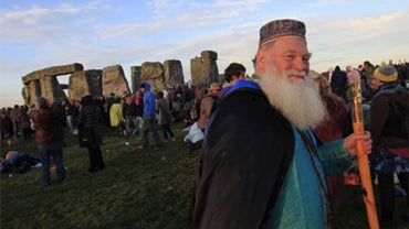 A Druids, name not given, walks past the Stonehenge monument, England, as he celebrates the summer solstice, Monday, June 21, 2010. 