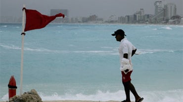 A life-guard stands next to a red flag meaning high hazard of high surf and/or strong currents as tropical storm Alex nears the region in the resort city of Cancun, Mexico, Saturday, June 26, 2010. 