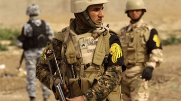 In this February 2010 file photo, a Kurdish Peshmerga (center) stands guard with an Iraqi policeman (left) and Iraqi Army soldier on their first patrol together as the Combined Security Force, on the outskirts of Kirkuk, north of Baghdad, Iraq.  
