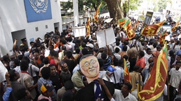 Sri Lankan protesters wave their national flags and block the entrance of the U.N. office in Colombo, Sri Lanka, Tuesday, July 6, 2010.  