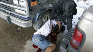 An unidentified police officer turns the body of a man killed by police at the Danziger Bridge in New Orleans 