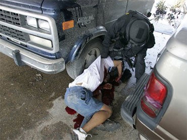 An unidentified police officer turns the body of a man killed by police at the Danziger Bridge in New Orleans 