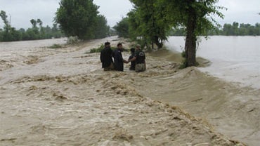 Pakistani police officers help each others to cross stream caused by heavy flooding in Bannu in northwest Pakistan on Sunday, Aug. 8, 2010. 