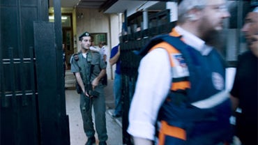 An Israel border police officer holds his weapon as a paramedic rushes put of the Turkish Embassy in Tel Aviv, Israel, Tuesday, Aug. 17, 2010. 