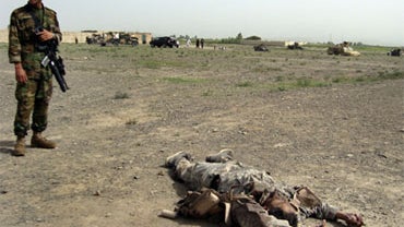 An Afghan National Army soldier stands near the body of a suicide attacker near a NATO base in Khost province of Afghanistan, Saturday, Aug. 28, 2010. 