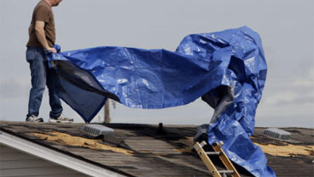 David Anderson covers his damaged roof with a blue tarp, Tuesday, Sept. 7, 2010 in Raymondville, Texas, after tropical storm Hermine swept through the area. 