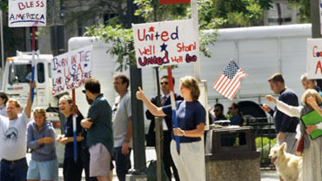 A gathering of well-wishers wave patriotic signs and shout encouragement as President Bush and his motorcade depart a prayer service at the National Cathedral in Washington, Friday, Sept. 14, 2001. 