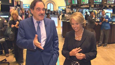 Director Oliver Stone walks with Katie Couric on the floor of the New York Stock Exchange. 