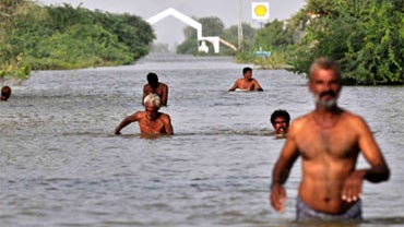 Pakistani flood survivors wade through floodwaters in Lalbakhash village on September 19, 2010. The United Nations gathered new aid pledges for the Pakistan flood disaster on September 19 after making a record two billion dollar appeal to feed millions of 