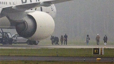 Two anti-terrorist policemen, center, secure one of the passengers as a Pakistan International Airlines Boeing 777 is evacuated at Stockholm Arlanda International airport September 25, 2010.  