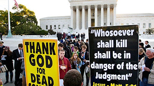 Westboro Baptist Church member Jacob Phelps, of Topeka, Kan., holds signs as people engage him in front of the Supreme Court  