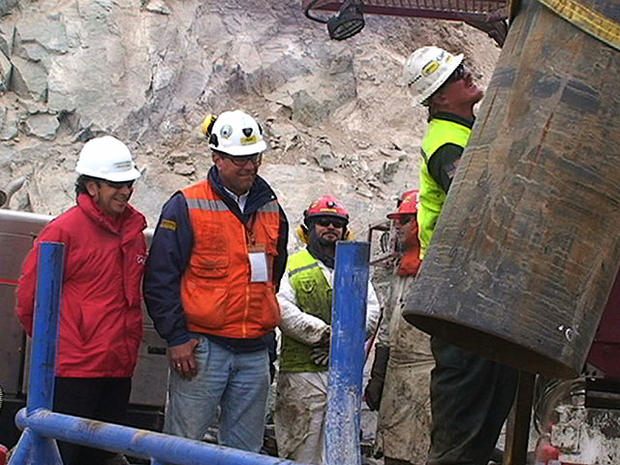 In this still image taken from a video released by the government of Chile on Oct. 10, 2010, Chile's Minister of Mining, Laurence Golborne, left, watches drill rig operator Jeff Hart, from Denver, Colorado, right, operate heavy machinery to lower steel pi 
