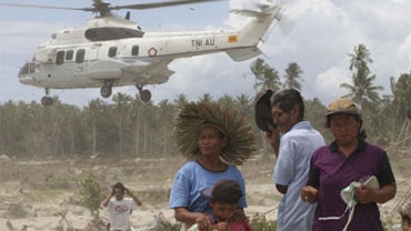 Tsunami survivors turn their face away from down wash created by a helicopter at Parorogat, Pagai island,West Sumatra, Indonesia, Thursday, Oct. 28, 2010. 