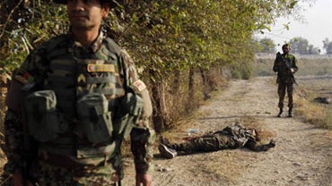 Afghan National Army soldiers stand guard near the body of a suspected Taliban fighter following the attack on the Jalalabad military airbase in Jalalabad, east of Kabul, Afghanistan, Saturday, Nov. 13, 2010. 