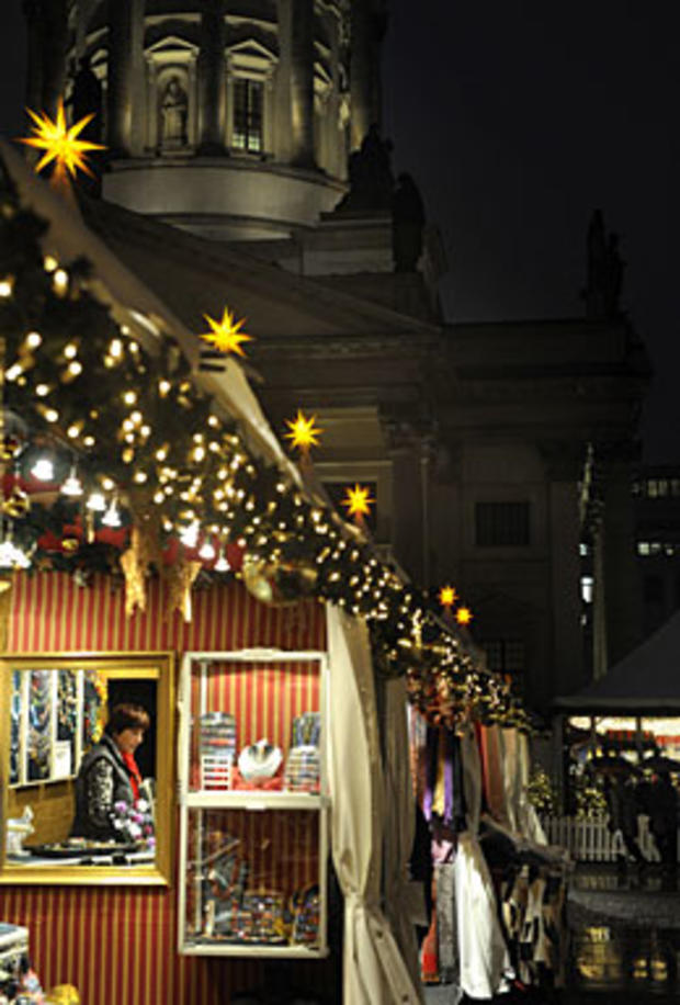 shopkeeper is reflected in the mirror as a few punters brave the rain to attend the opening day of the Christmas market at Gendarmenmarkt in Berlin, November 22, 2010 as the Christmas season starts with markets, decorated streets and shopping arcades star 