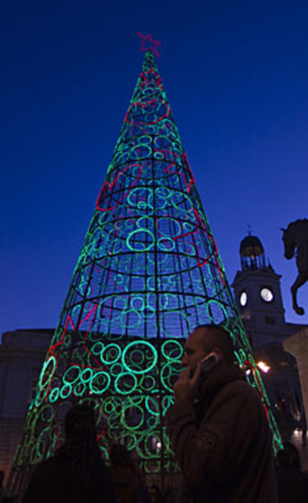 aman walks past an illuminated Christmas tree in Madrid Wednesday Dec. 15, 2010. (AP Photo/Paul White) 