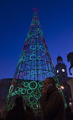 aman walks past an illuminated Christmas tree in Madrid Wednesday Dec. 15, 2010. (AP Photo/Paul White) 