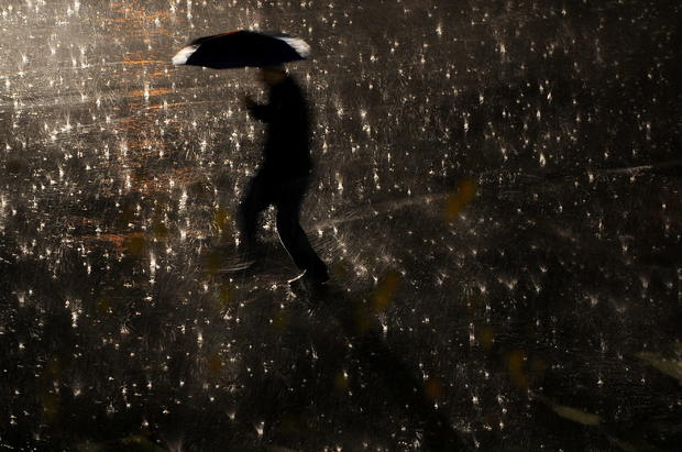 A man walks with his umbrella during a night rain storm 