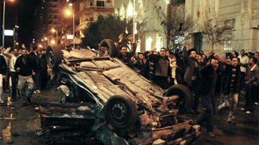 Worshippers shout around an exploded car in front of a Coptic Christian church in the Egyptian city of Alexandria, Egypt, early Saturday Jan. 1, 2011. The car exploded in front of the church as worshippers emerged from a New Year's Mass in the Mediterrane 