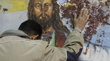 An Egyptian Christian mourns as he stands next to a blood-stained painting of Jesus Christ on January 2, 2011 outside the Al-Qiddissine (The Saints) church in Alexandria, following a New Year's Eve car bomb attack on the Coptic church in the northern Egyp 